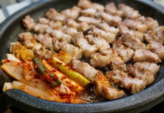 둥근 불판에서 한입 크기로 잘라 구운 삼겹살과 김치·대파